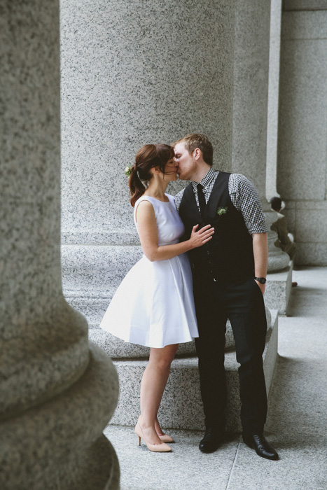 bride and groom kissing outside city hall