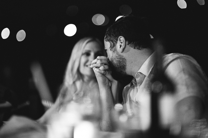 groom kissing bride's hand at reception