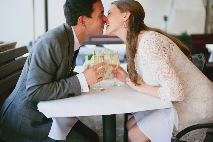 bride and groom kissing over champagne