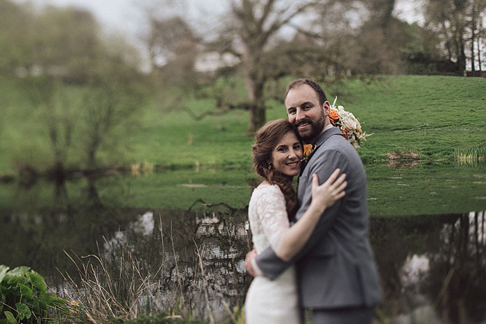 bride and groom embracing by pond