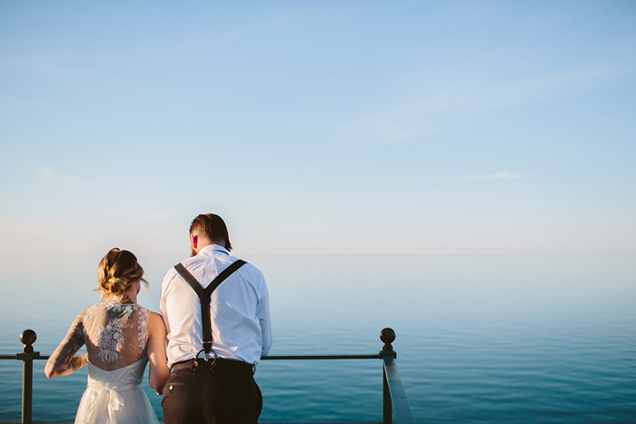 bride and groom looing over lighthouse railing