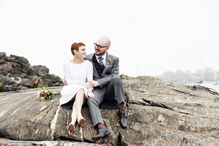 bride and groom sitting on the rocks