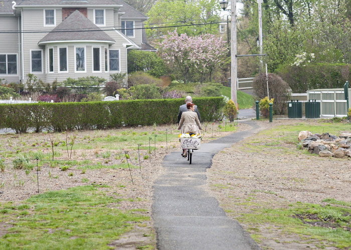 bride and groom riding away on tandem bike