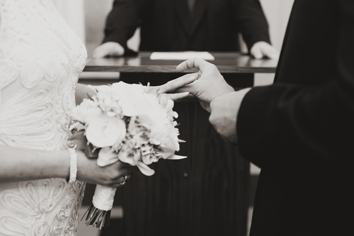 groom putting ring on bride's finger