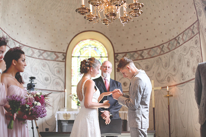 groom putting ring on bride's finger