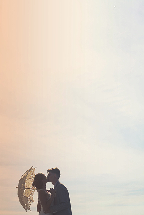 bride and groom kissing under parasol