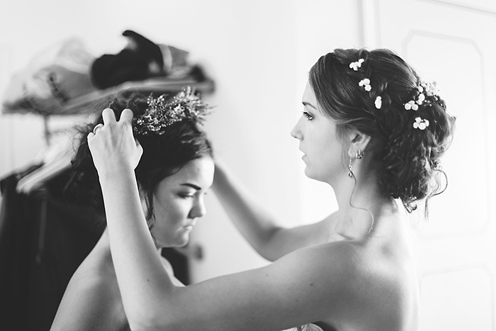 bride placing flower crown on bridesmaid