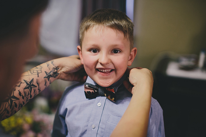 groom putting bow tie on his son