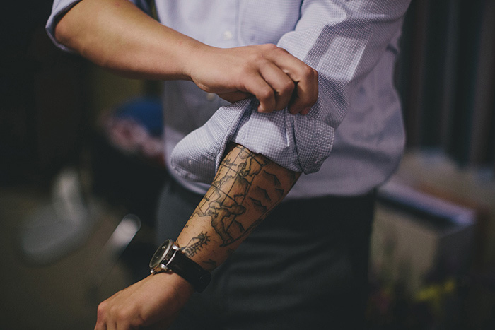 tattoed groom rolling up his sleeves