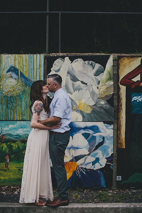 bride and groom kissing in front of mural