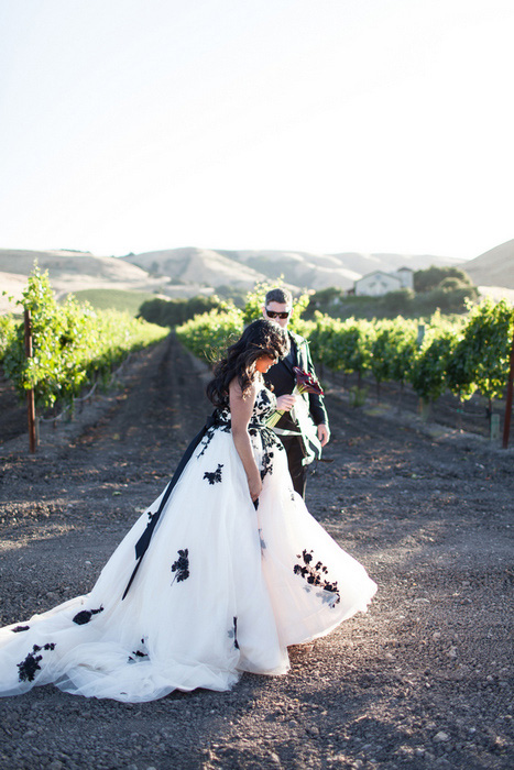 bride and groom walking next to grape vines