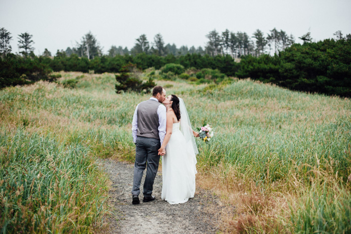 bride and groom kissing in field