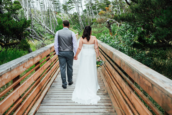 bride and groom walking across wooden bridge