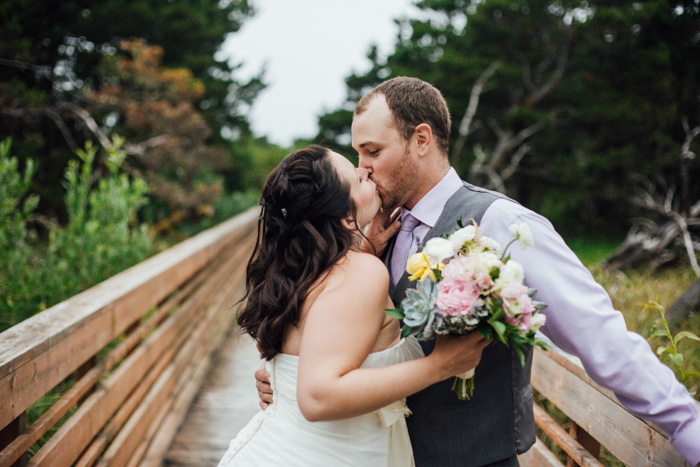 bride and groom kissing on bridge