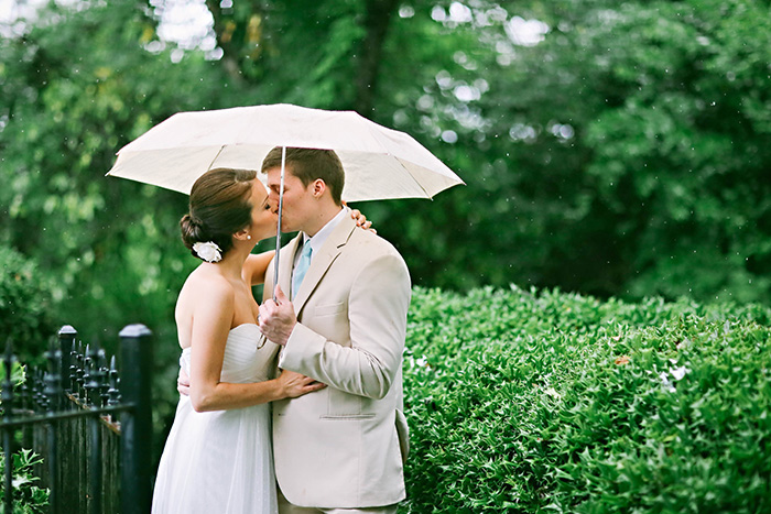 bride and groom kissing under umbrella