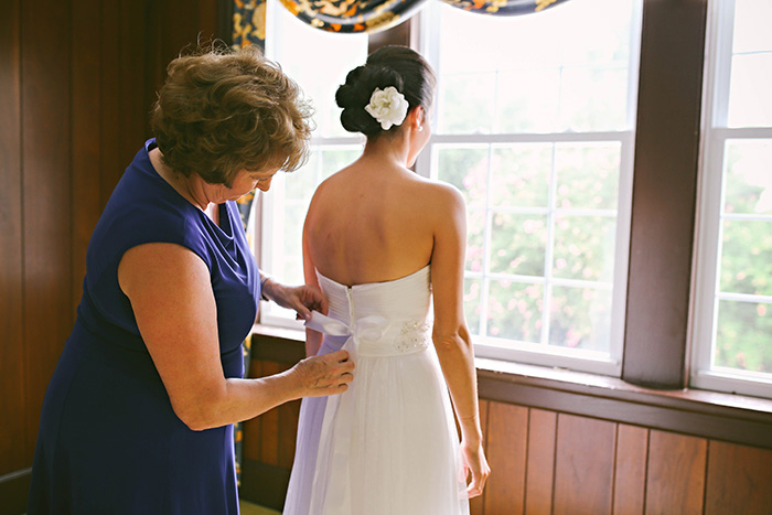 mother helping bride with her dress