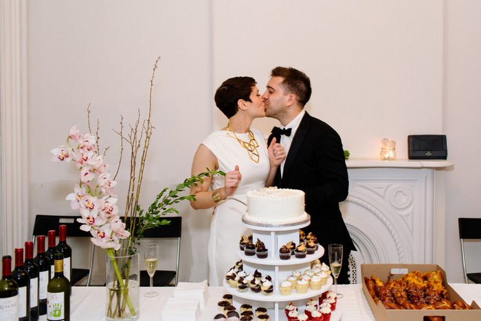 bride and groom kissing in front of cake