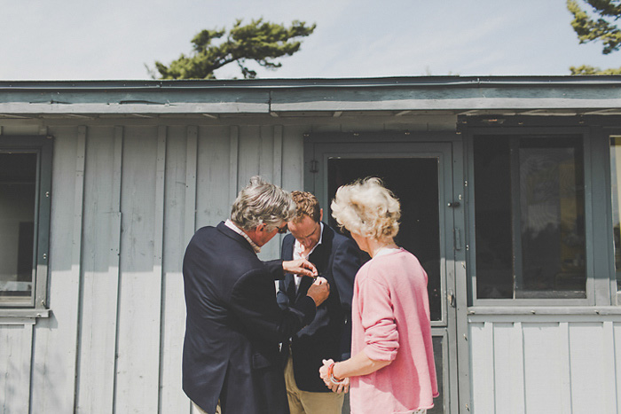 parents pinning boutonniere on groom