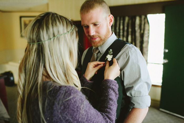 bride pinning boutonniere on groom