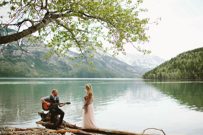 groom serenading bride by the lake