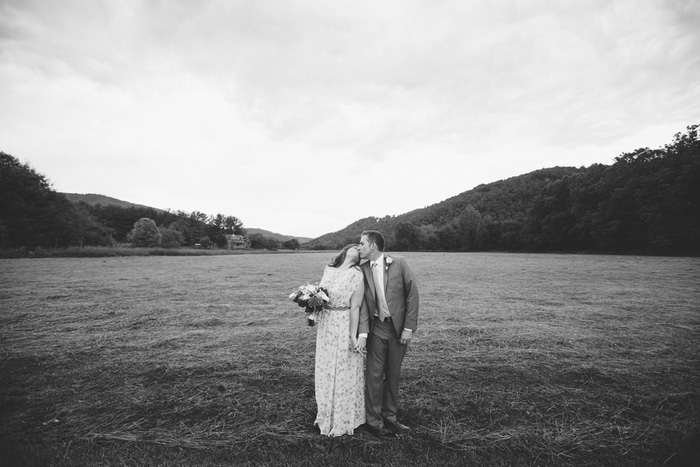 bride and groom kissing in field