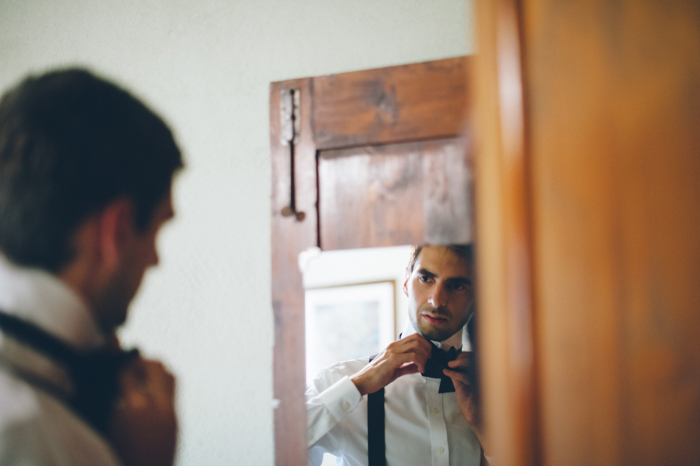 groom tying his bow tie