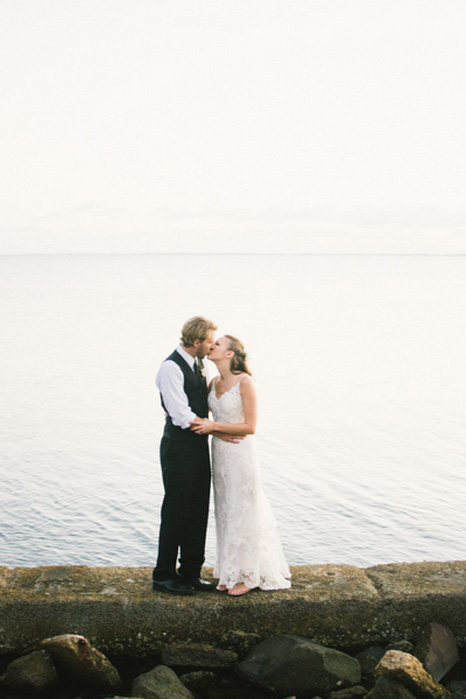 bride and groom kissing by the ocean
