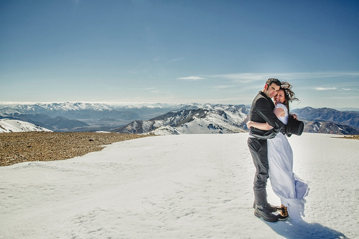 bride and groom hugging on windy mountain top