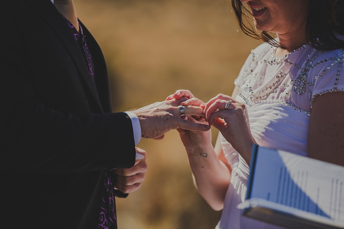 bride putting ring on groom's finger