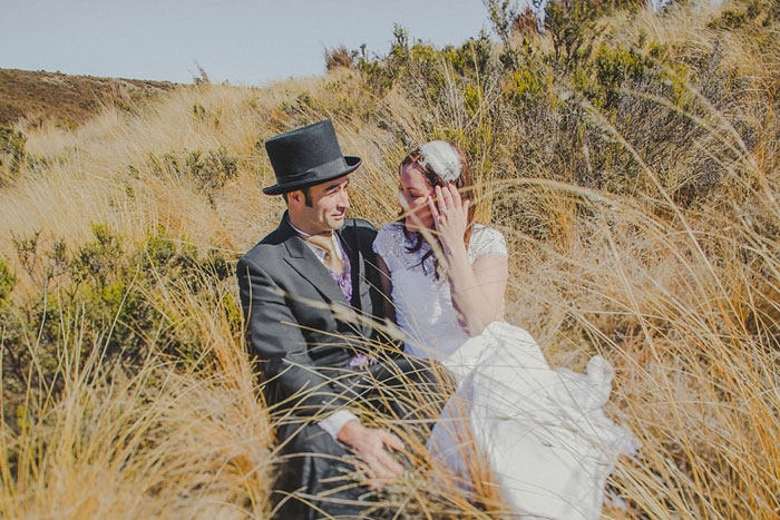 bride and groom sitting in field