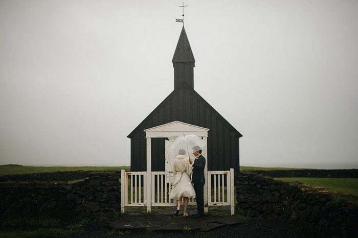 bride and groom in front of black chapel