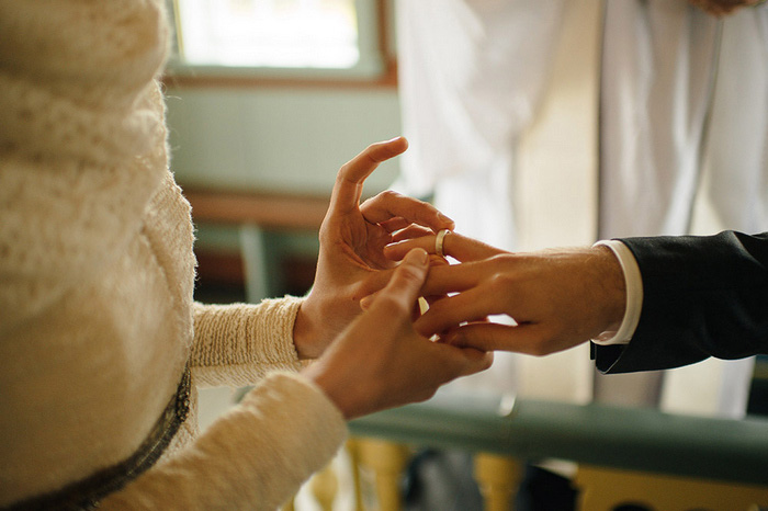 bride putting ring on groom's finger