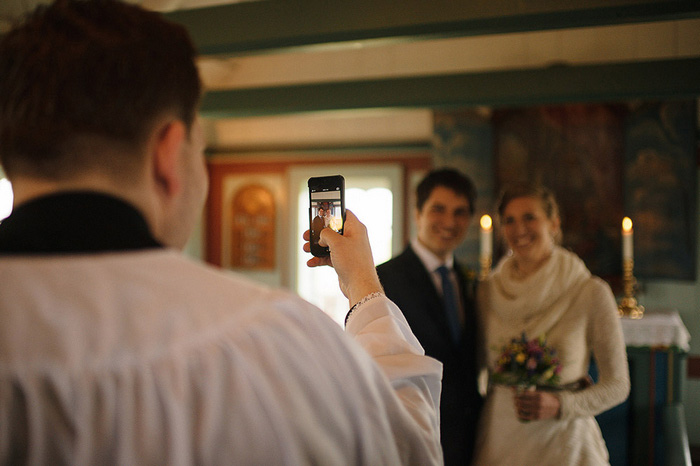 officiant taking phone photo of bride and groom