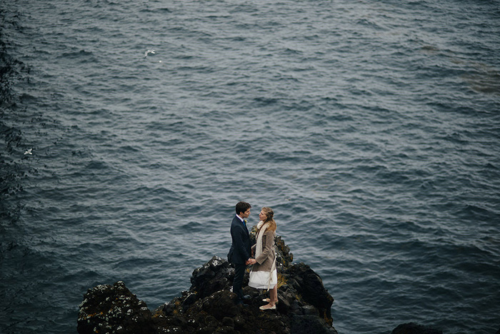 bride and groom standing by ocean