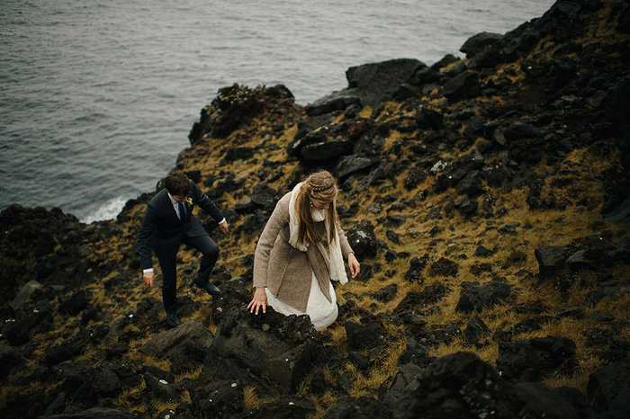 bride and groom climbing rocks