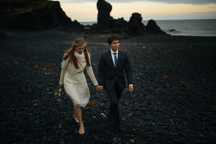 bride and groom walking on black rock beach