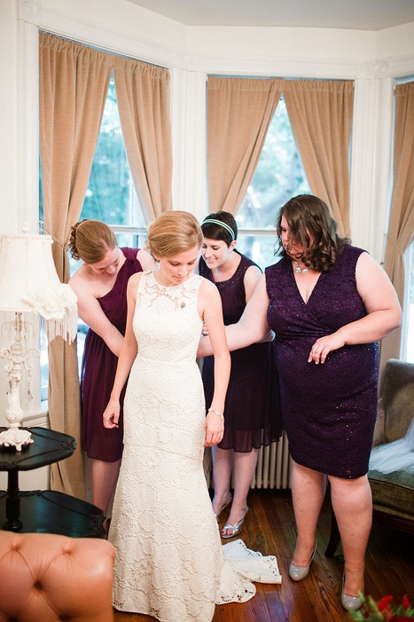 bridesmaids helping bride get dressed