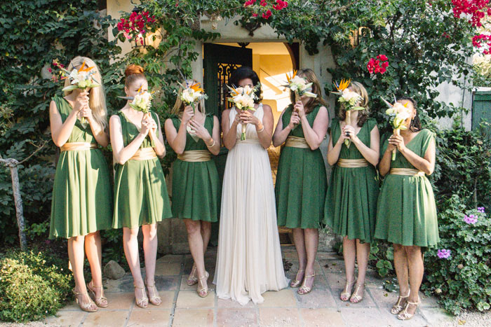 bridal party holding bouquets in front of faces