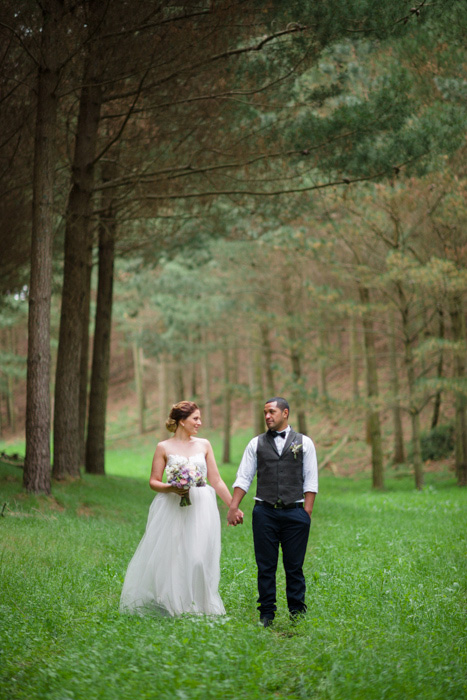 bride and groom holding hands in the woods