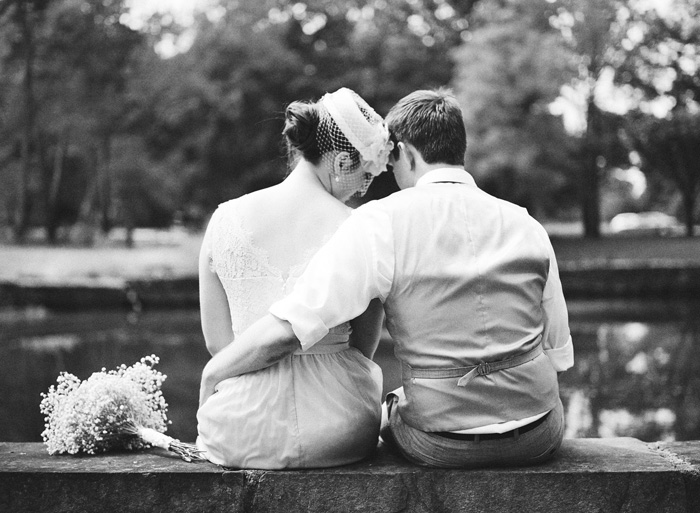 bride and groom sitting by pond