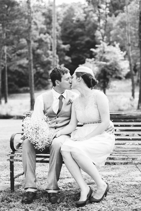 bride and groom kissing on bench