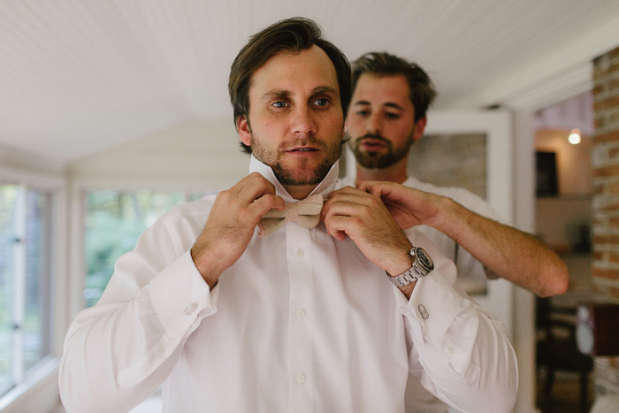 groom tying bow tie