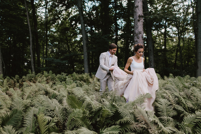 groom holding bride's dress as the walk