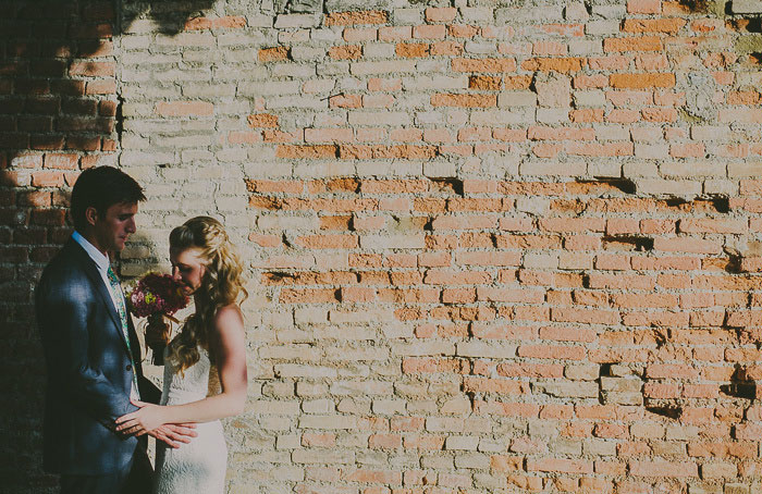 bride and groom portrait against brick wall