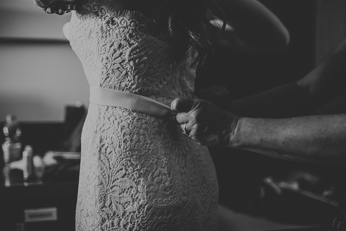 bride having her dress buttoned up