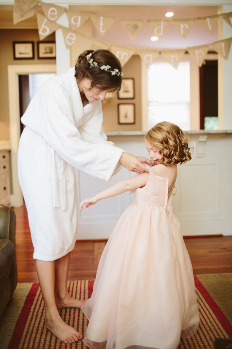 bride helping flower girl get dressed