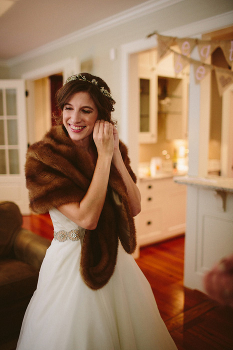 bride in fur stole putting on earrings