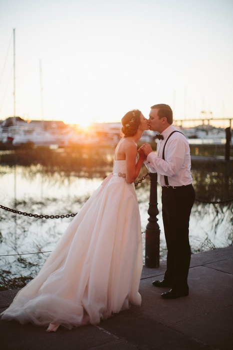 bride and groom kissing at sunset