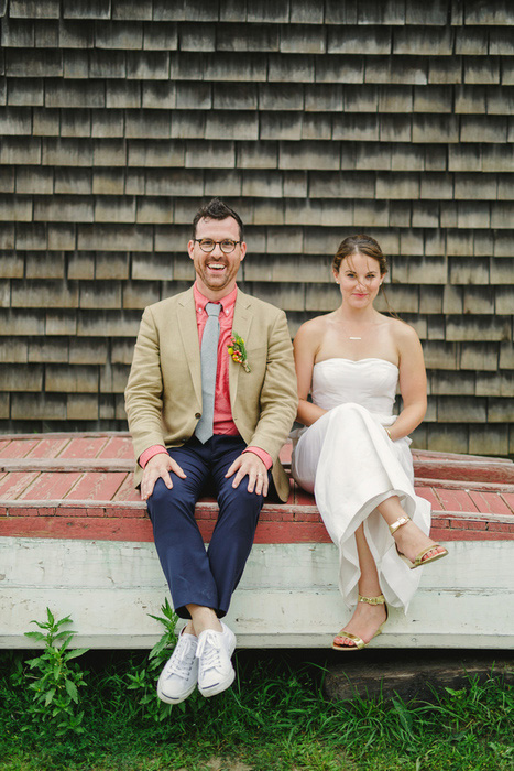 bride and groom sitting on overturned boat