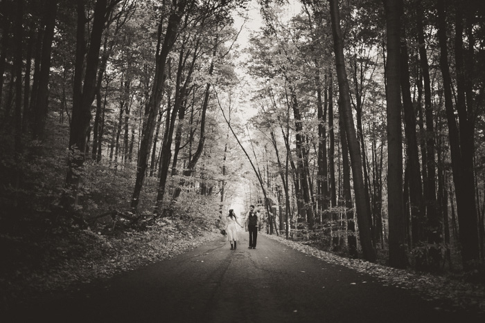 bride and groom walking down wooded road